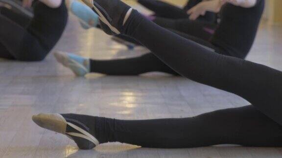 一群年轻的芭蕾舞演员在芭蕾课上练习双腿