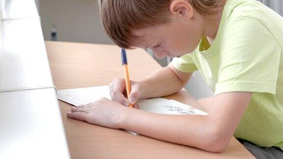小学生坐在桌子旁学习写字母做家庭作业