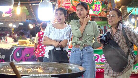泰国街头小吃她们来市场观光那里是夜生活的场所是吃饭的好地方