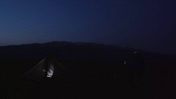 成熟的游客晚上在帐篷里用手机在大自然中独自在山上露营