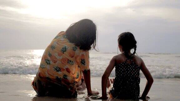 母亲和女儿亚洲人在海滩上玩日落