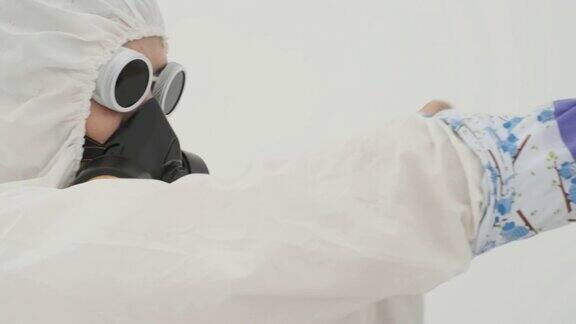 特写镜头中的男子身穿白色化学防护服戴着防毒面具戴着一只紫色的橡胶防护手套