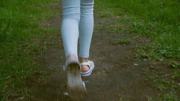 少女的腿在蓝色打底裤和凉鞋走然后在草地上跑步走着女人的腿在夏天的草鞋在绿色的草地上后视镜