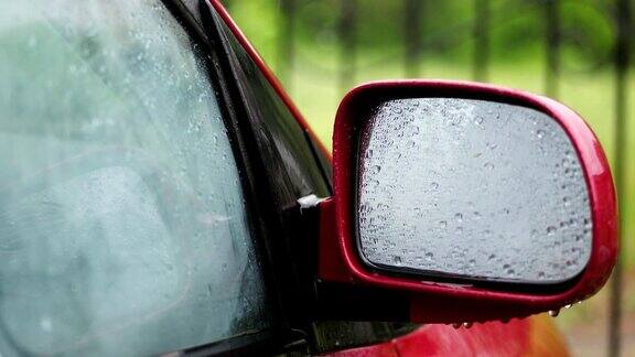特写镜头雨点在汽车的玻璃窗上滴落下来雨点落在侧面的镜子上有大雨阵雨雨滴落在汽车玻璃上