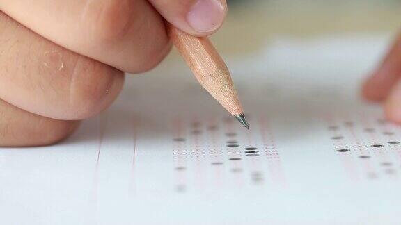 考试考试学校或大学:手握铅笔写标准化的答案多复写纸形式与灰黑色的答案表泡泡做期末评估在教室