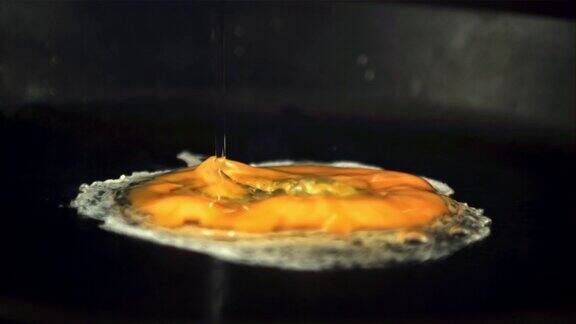 超级慢动作的生鸡蛋落在热煎锅上用高速摄像机以每秒1000帧的速度拍摄