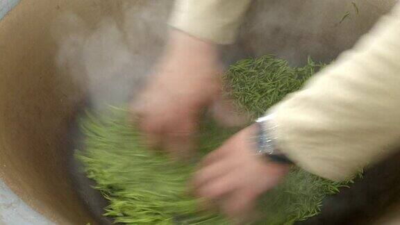 农场工人用中国传统的方式在钢锅里炒茶