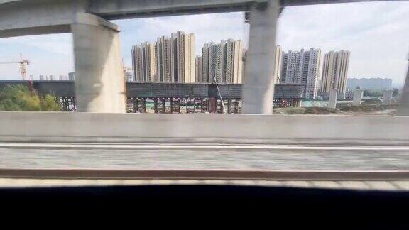 在火车上望向窗外经过城市中正在建设的火车桥