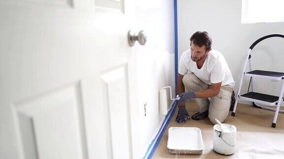 油漆工在家里粉刷墙壁用油漆滚筒和白色油漆室内装修4k