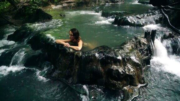 在温泉瀑布中沐浴的女人