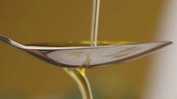 把新鲜橄榄油倒在勺子上将葵花籽油倒入勺内浇在黄色的液体上从玻璃瓶中倒橄榄油从勺子里倒橄榄油