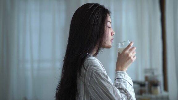 面部表情由年轻女子在纯净的早晨时间喝牛奶