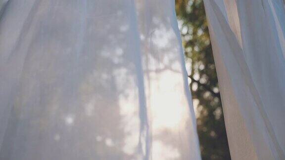 白色透明窗帘布在阳光的吹拂下随风飘扬