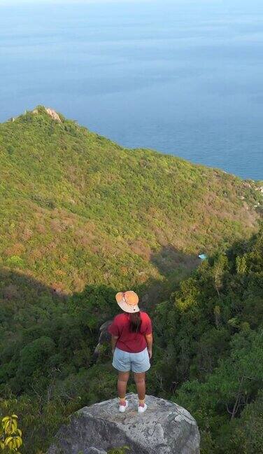 亚洲女孩徒步旅行到山顶的岛屿山的观点放松和冷却泰国kohtao