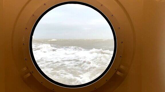 透过舷窗看到暴风雨的海面上海浪击打着船