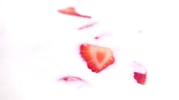 两段草莓落入酸奶的慢动作视频