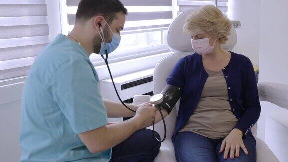 医生戴上防护口罩用测量仪测量女患者的血压