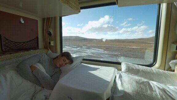 特写:疲惫的女孩睡在卧铺里在火车穿越西藏的旅途中
