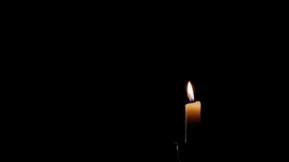 时间的流逝一个单一点燃的蜡烛火焰燃烧所有的方式下来的黑色背景