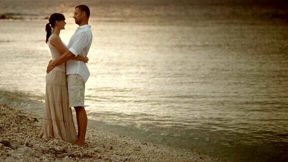 一对恩爱的情侣在海边拥抱聊天