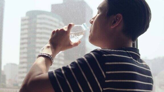 年轻的亚洲人喝玻璃杯里的水