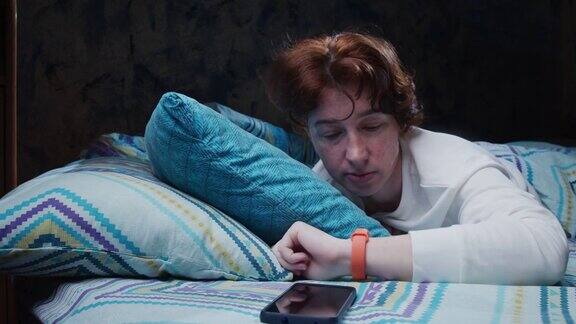 床上的成熟女人正在醒来戴上智能腕带