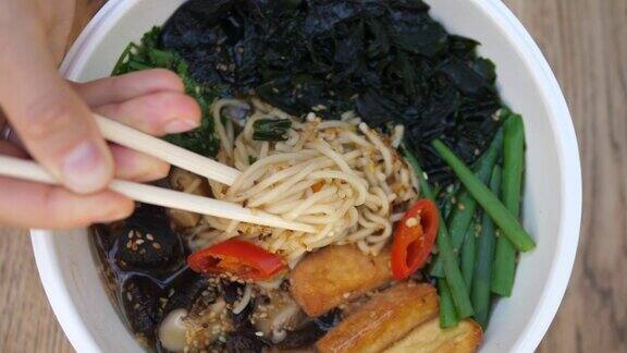 最上面的镜头是筷子从素食拉面汤中拔出面条健康的有机素食饮食