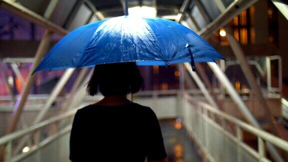 女人撑着伞走在人行桥上