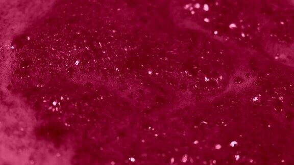 覆盆子果酱泡沫烹饪果酱从浆果樱桃草莓丰富的红色甜配置与泡沫厚泡沫粉红色起泡液体沸腾的质地小红莓果酱的微距镜头品红色的