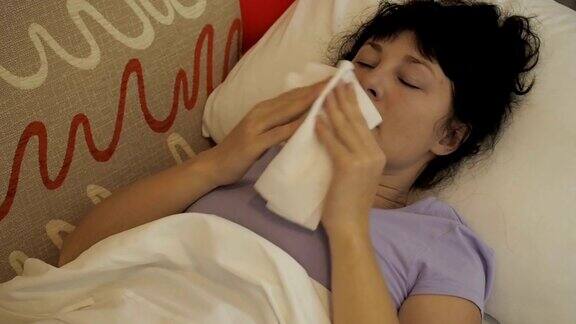 一个生病的女人坐在家里的沙发上打喷嚏女孩流鼻涕拿纸巾流感症状医疗保健和医疗理念感冒是流感的感染