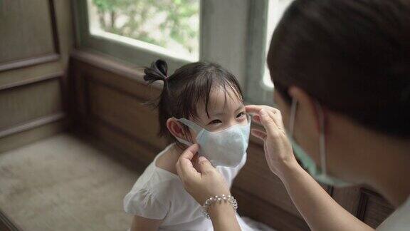 亚洲母亲为女儿戴医用口罩COVID-19手持拍摄