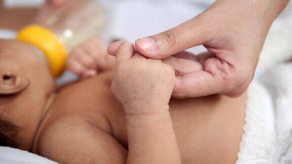 母亲用奶瓶喂亚洲男孩或儿子婴儿用爱握住母亲的手指慢动作