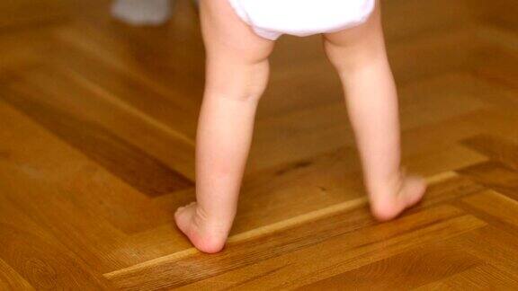 小脚在地板上走婴儿学习走路的特写