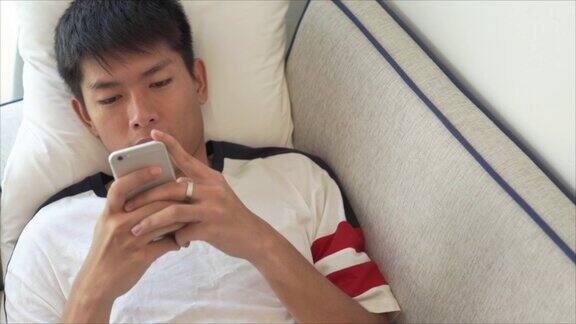 年轻的亚洲商人使用数码平板电脑和智能手机在家里工作并在他的职业生涯中通过网上购物放松