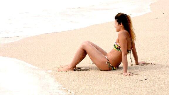 迷人的女人在希腊海滩在夏天日光浴比基尼