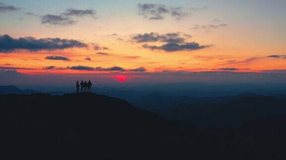四个朋友站在美丽的日出的山上
