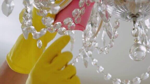 室内清洁特写镜头双手戴着黄色橡胶防护手套用干抹布擦拭房间里的吊灯一般或定期清洁保洁服务