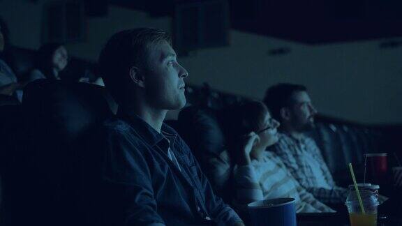 一群年轻人在电影院看电影吃着爆米花面带微笑