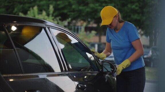 穿着制服的女人用海绵清洁汽车洗车服务