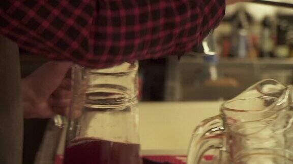 酒保将水果饮料从酒壶倒入玻璃杯中瓶装的自制红酒