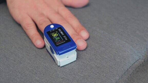 男子使用手指上的数字脉搏血氧计医疗监测和显示氧饱和度水平近距离观察