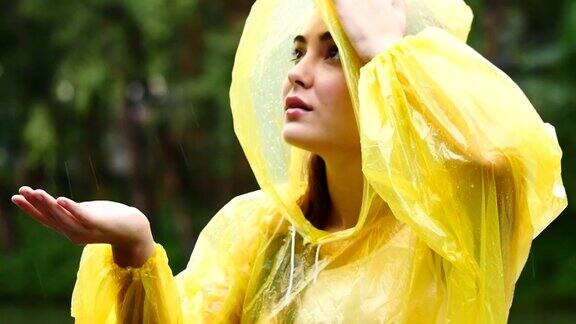 穿着黄色雨衣的年轻美丽幸福的女人享受着雨