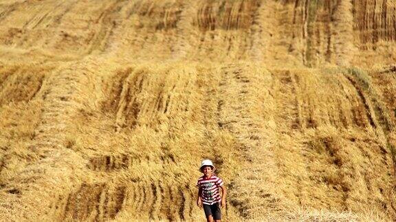 小男孩在黄色的田野里奔跑小男孩在割过的田野里奔跑小男孩在稻草里奔跑