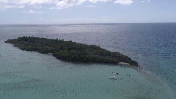 岛屿被温暖的海水包围绿松石色的船和潜水员在委内瑞拉加勒比海的洛斯罗克国家公园鸟瞰图无人机在岛屿上空旋转4k
