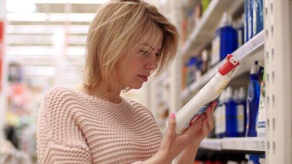 一位30多岁的自信女性买家在室内商店挑选家用化学品帅气女孩专注于搜索出售的生物瓶必需品手握分析选择部门近距离4k