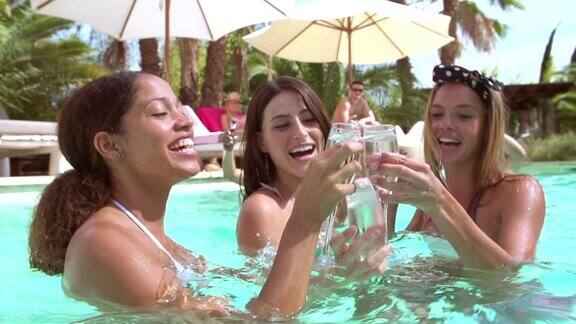 三个女人在游泳池里开派对喝香槟
