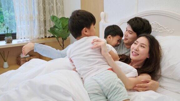 台湾的爸爸妈妈和他们的孩子在床上玩