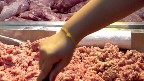 展示肉类产品女人的手用不锈钢手柄在超市选购生猪肉