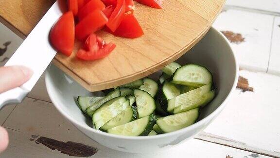 女厨师准备新鲜蔬菜的健康沙拉素食在家庭厨房里把番茄切片和沙拉一起倒进碗里