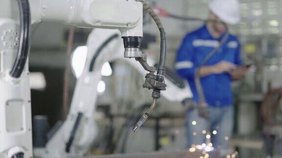 年轻人工程师检查和控制焊接机器人自动手臂机器在智能工厂工业机器人科学和技术工业自动化机器人概念